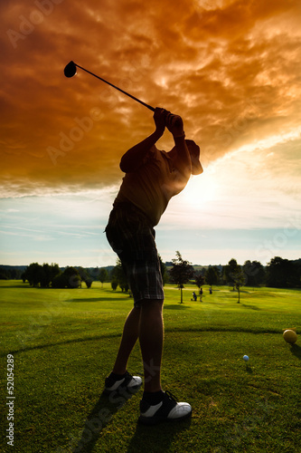 Photo: Young golf player on course doing golf swing Young golf player on course doing golf swing