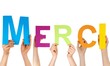 hands holding the letters MERCI