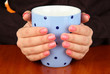 Hands holding mug of hot drink, close-up