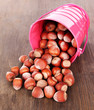 Overturned bucket with hazelnuts on wooden background