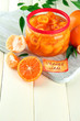 Orange jam with zest and tangerines, on white wooden table