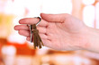 Key with leather trinket in hand on bright background
