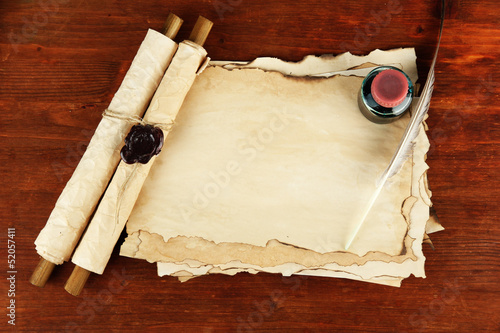 Photo: Old paper, ink, scrolls and feather on wooden background Old paper, ink, scrolls and feather on wooden background