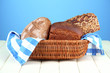 Bread in wicker basket, on wooden table, on color background