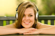 Beautiful smiling girl listening to music while sitting outdoor