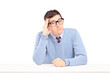 Foto: Doubtful guy sitting and thinking on a table Doubtful guy sitting and thinking on a table
