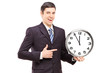 A young man in suit pointing on a clock