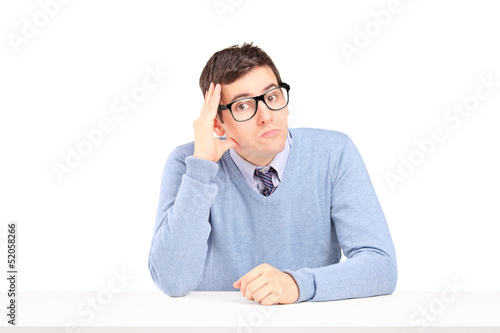 Photo: Doubtful guy sitting and thinking on a table Doubtful guy sitting and thinking on a table