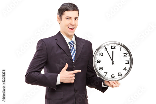 Photo: A young man in suit pointing on a clock A young man in suit pointing on a clock