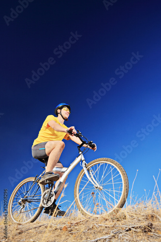 Photo: A young male wearing yellow shirt and helmet on a bike A young male wearing yellow shirt and helmet on a bike