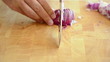 Caucasian man cutting onion on yellow colored wooden desk