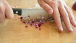 Caucasian man cutting onion on yellow colored wooden desk