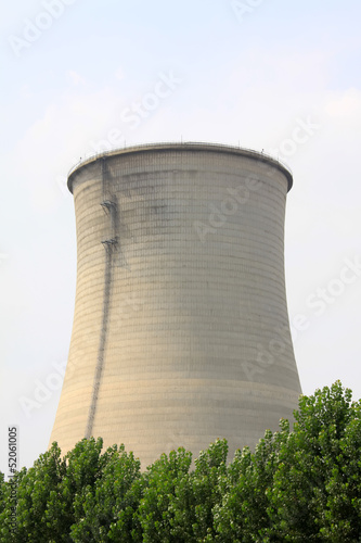 Photo: heavy industrial water cooling tower and the green tree heavy industrial water cooling tower and the green tree