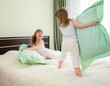 two girls playing with pillows in bedroom