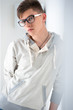 Portrait of young fashionable man leaning on white wall and wear