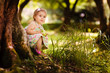 Foto: Cute baby girl eating apple at sunny beautiful garden background Cute baby girl eating apple at sunny beautiful garden background