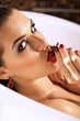 Young brunette girl taking a bath and eating strawberry