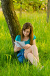 Beautiful teenage girl reading letter in the nature