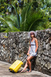 Girl with a yellow suitcase on a resort