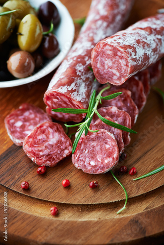Photo: Salami and rosemary on wooden chopping board Salami and rosemary on wooden chopping board
