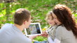 Happy family using tablet PC outdoors in autumn park