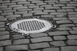 Photo: Old sewer manhole on dark cobblestone pavement Old sewer manhole on dark cobblestone pavement