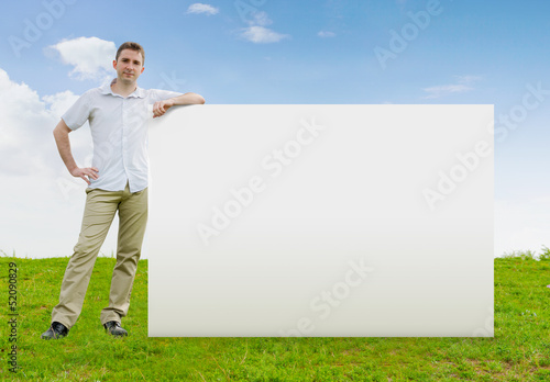 Photo: Man standing in a field with a large blank sign Man standing in a field with a large blank sign