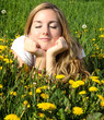Young woman relaxing between dandelions