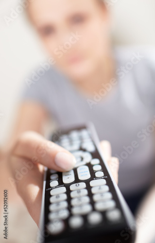 Photo: Young woman with remote watching TV. Young woman with remote watching TV.