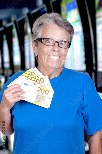 Photo: Dame âgée tenant dans la main une liasse de billets. Dame âgée tenant dans la main une liasse de billets.
