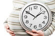 Pregnant woman hand holding large office wall clock showing time
