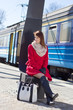 Photo: young beautiful woman in red waiting for train on the platform young beautiful woman in red waiting for train on the platform