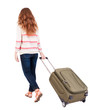 Photo: back view of walking woman with suitcase. back view of walking woman with suitcase.