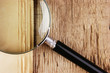 edge of the old newspaper and magnifying glass on a wooden backg