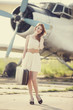 Lonely girl with suitcase at near airplane.