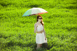 Redhead enchantress with umbrella and suitcase at spring country