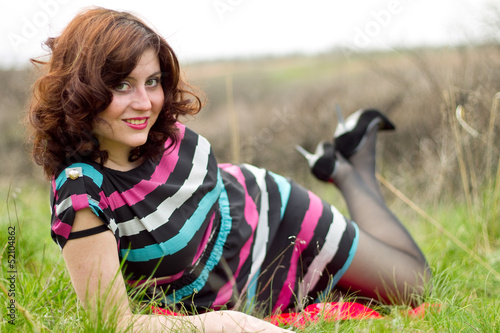 Photo: A young girl in a dress and tights posing in spring wood A young girl in a dress and tights posing in spring wood