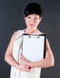 Photo: serious business woman with blank over dark background serious business woman with blank over dark background