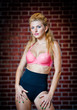 girl in swimsuit posing provocatively in front of a brick wall