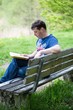 Man sitting on a bench and reading a book