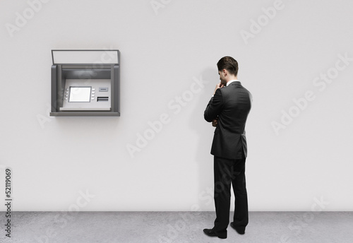 Photo: man looking at atm man looking at atm
