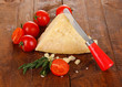 Piece of Parmesan cheese with knife on wooden table close-up