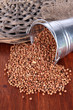 Overturned bucket with grains on wooden background