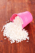 Overturned bucket with grains on wooden background