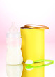 Bottle with milk and food for babies on pink background