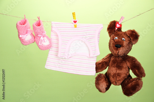 Photo: Baby clothes hanging on clothesline, on color background Baby clothes hanging on clothesline, on color background