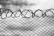 Iron fence with a barbed wire and stormy sky.