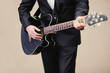 Closeup of a man in suit  playing an acoustic guitar