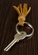 Key with leather trinket on wooden background