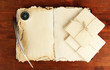 Open old book, letters and compass on wooden background